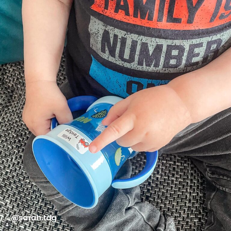 Lite barn fester navnelapp på drikkeflaske