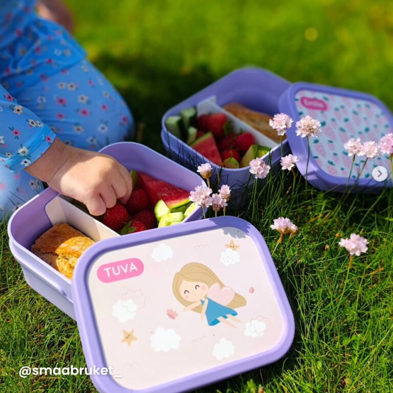 jente som sitter i gresset med lilla matboks