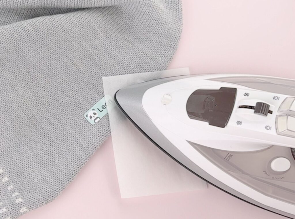 strykelapp med panda som festes på en grå barneullbukse