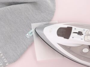 strykelapp med panda som festes på en grå barneullbukse