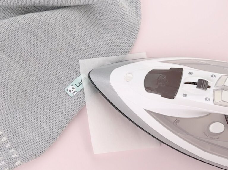 strykelapp med panda som festes på en grå barneullbukse