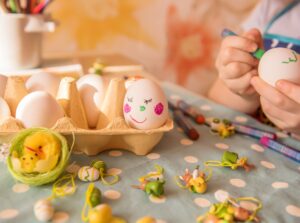 Påskeverksted-Eggekartong fylt med malte egg og et bord dekket med påskepynt